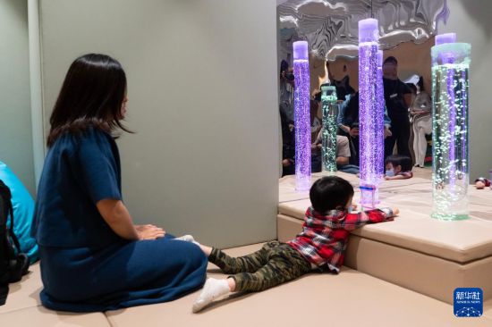 在位于香港国际机场一号客运大楼的“感知阁”内，邓女士陪伴被诊断为孤独症的儿子玩耍（3月31日摄）。 新华社发（龙镜伊 摄）  　　以光影与声音抚平焦躁